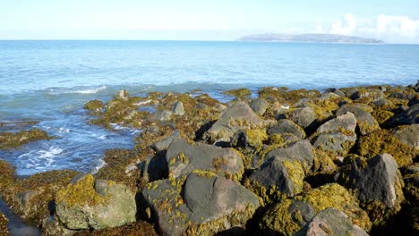 Clear-blue-ocean-stone-pebble-beach-coastline-island-holiday-horizon-scene