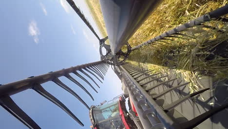 POV-perspective:-rotating,-circling,-and-oscillating-farm-combine-harvester-busy-harvesting-brown-wheat,-dizzy,-falling-concept,-close-up