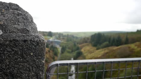 Heavy-stone-wall-metal-barrier-fence-overlooking-Welsh-valley-countryside-dolly-right