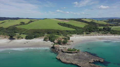 Overflying-The-Crystal-Clear-Blue-Water-Of-The-Pacific-Ocean-With-A-Scenic-View-Of-Tawharanui-Regional-Park-In-Auckland,-New-Zealand-In-Summer