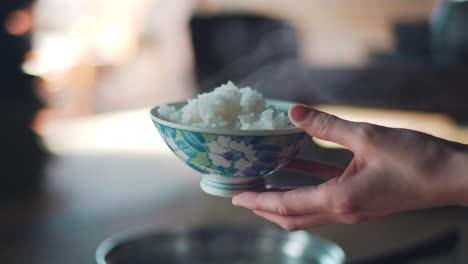 Hand-Holding-A-Floral-Japanese-Bowl-Of-A-Steaming-Hot-Rice