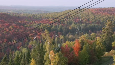Empty-Ski-Chair-Lift-With-Brilliant-Fall-Colors-In-The-Background