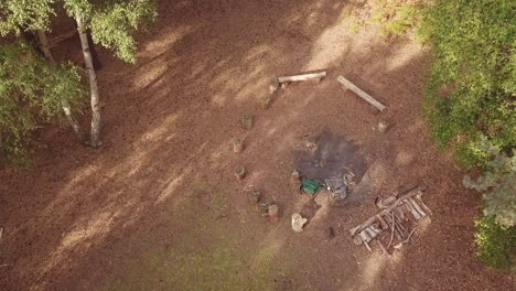 Drone-shot-jibbing-down-over-campfire-site-with-log-seats-and-two-camping-chairs