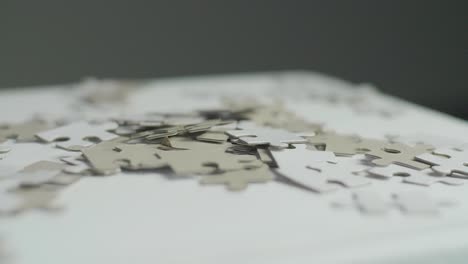 White-and-gray-puzzle-pieces-laying-randomly-on-a-white-surface-with-a-dark-background