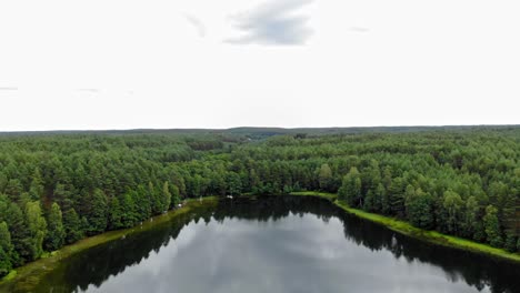 Calm-Lake-Surrounded-By-The-Lush-Green-Coniferous-Forest-At-Daytime-In-Pradzonka,-Gmina-Studzienice,-Poland