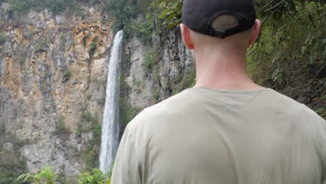 Young-caucasian-man-walking-towards-Sipiso-Piso-Waterfall-in-North-Sumatra,-Indonesia