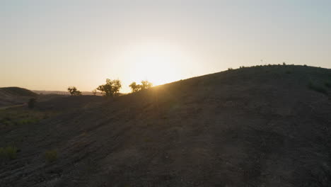 Luftbildaufnahme,-Die-Einen-Wunderschönen-Sonnenaufgang-Hinter-Einem-Hügel-Zeigt,-Der-Durch-Einen-Feldweg-Zum-Horizont-Geteilt-Wird,-In-Der-Algarve,-Portugal