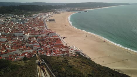 Amazing-panoramic-view-of-the-ocean,-beautiful-sandy-beach,-small-town-and-2-funicular-cars