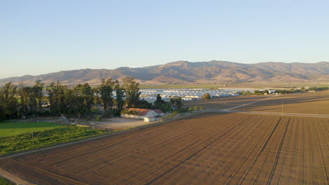 Forqward-and-pan-left-of-large-farmland-with-mountains-in-the-background-in-Salinas-Valley,-CA