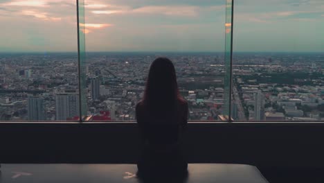Girl-sits-and-looks-at-Bangkok-view-on-Baiyoke-tower-rooftop-at-sunset