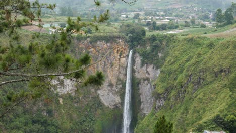 Slow-motion-shot-from-view-of-water-falling-down-at-Sipiso-Piso-Waterfall-in-North-Sumatra,-Indonesia---camera-tilting-down