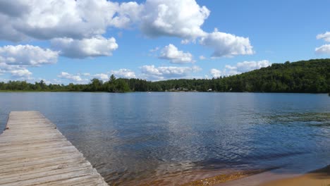 Beautiful-Canadian-Lake-Pan---Cottage-Wooden-Dock-with-Pine-Trees-and-Fluffy-Clouds-on-Horizon
