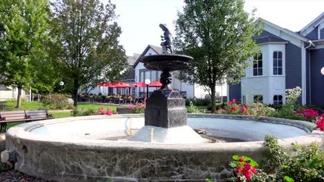 Empty-fountain-on-a-sunny-afternoon-surrounded-with-flowers,-wide-shot