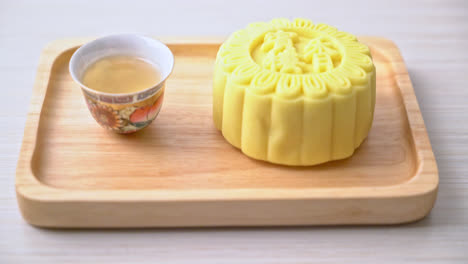 Chinese-moon-cake-custard-flavour-with-tea-on-wood-plate