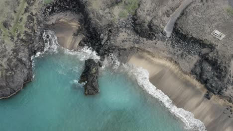 Aerial-of-famous-Skardsvik-beach-with-turquoise-water-and-rocky-cliff-in-Iceland
