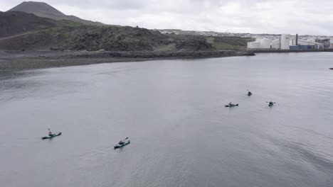 Drone-Volando-Sobre-Un-Grupo-De-Kayakistas-Oceánicos-Remando-Hacia-La-Isla-Heimaey