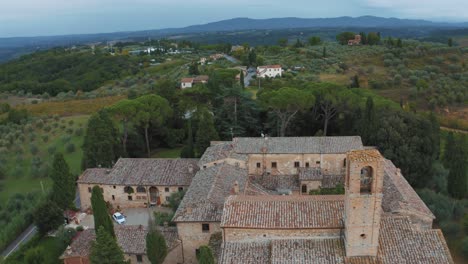 Aerial-drone-footage-of-an-old-estate-close-to-San-Gimignano-near-Siena-in-the-idyllic-landscape-of-Tuscany,-Italy-with-vineyards,-hills-and-olive-trees-around