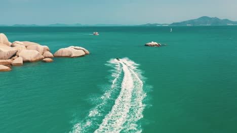 Aerial-drone-shot-of-jet-ski-couple-cruising-in-high-speed-in-tropical-exotic-bay-with-emerald-sea