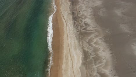 Abstract-scenery-of-waves-giving-natural-shapes-to-sand-beach-in-Iceland,-aerial