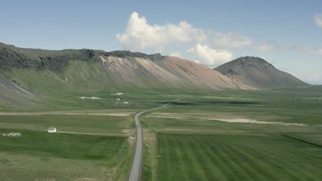 Aerial-of-vast-green-landscape-with-elevated-mountains-on-sunny-day,-Iceland