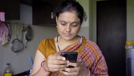 indian-women-using-mobile-in-kitchen-getting-inspired-disappoint
