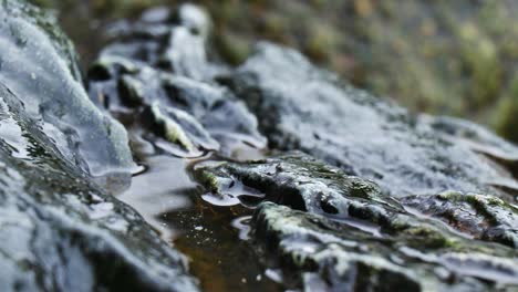 Macro-of-eroded-rocks-full-of-water,-rain-coming-down