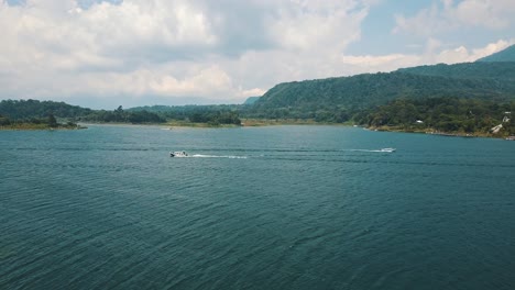 Drohnenantenne,-Die-Mit-Reisenden-Booten-In-Guatemala,-Mittelamerika,-über-Bäume-In-Richtung-Lake-Atitlan-Fliegt