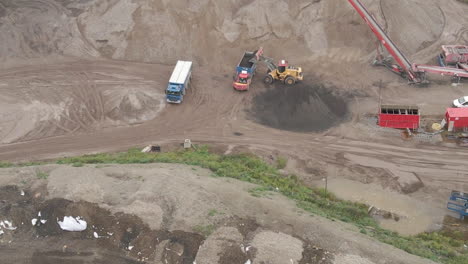 Aerial-of-excavator-dumping-sand-in-truck---close