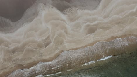 Sandy-beach-with-waves-crashing-on-shore-of-Snæfellsnes-peninsula,-top-down-shot