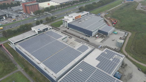 Aerial-of-industrial-rooftop-filled-with-solar-panels-near-busy-highway