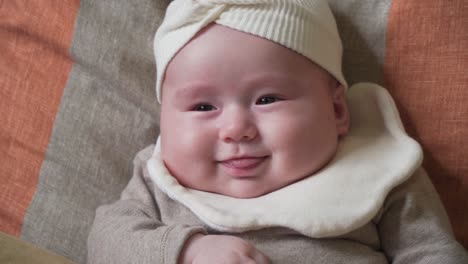 Entzückendes-Kleinkind-Baby-Mädchen-Gesicht-Nahaufnahme-Auf-Kissen-Liegend-Und-Lächelnd-Ihre-Zunge-Zeigend