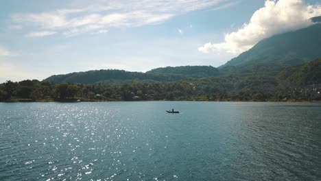 Amazing-Drone-aerial-flying-over-a-man-paddling-on-a-boat-in-lake-Atitlan,-Guatemala