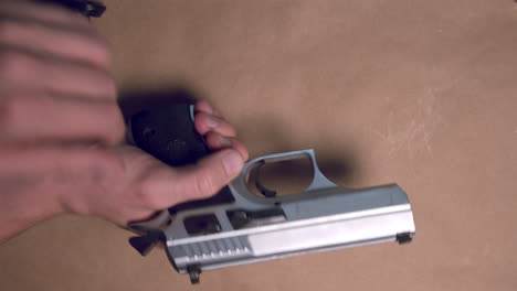 Male-hand-taking-firearm-gun-off-table-and-unloading-magazine-with-bullets