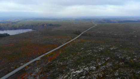 Aerial-view-showing-a-motor-cycle-riding-through-an-old-wild-fire-area-on-a-foggy-autumn-evening