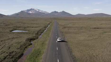 Car-travels-on-long-road-in-middle-of-Icelandic-landscape-with-endless-view