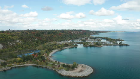 Drone-shot-flying-over-water-towards-land,-bluffs,-peninsula-with-green-trees