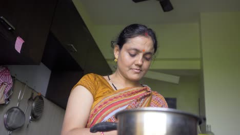 indian-women-in-kitchen-making-tea-and-using-mobile-low-angle-shot