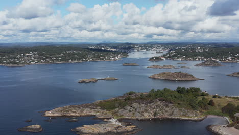 Aerial-High-Pan-of-seaside-Arendal-cityscape-with-white-clouds,-Norway