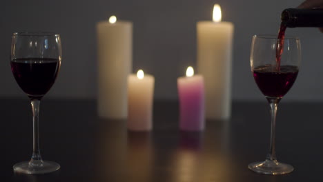 Glas-Rotwein-Wird-Am-Kerzenbeleuchteten-Esstisch-Gegossen
