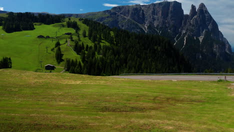 Man-bikes-downhill-through-Dolomites-in-Italy,-Aerial-Shot
