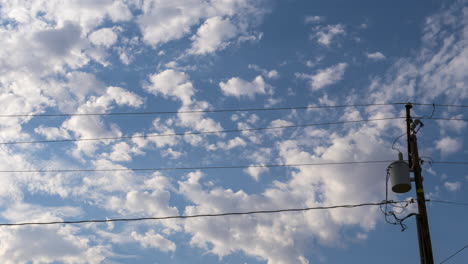 Fluffy-clouds-float-by-over-the-power-lines---time-lapse-cloudscape