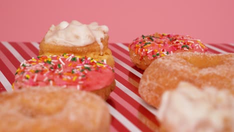 Delicious-pink-and-white-donuts-with-cream-and-sprinkles---camera-shifting-focus-as-it-slide-out