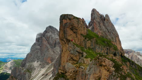 Man-in-distance-runs-to-cliff-of-Seceda-peak-Italy-Dolomites