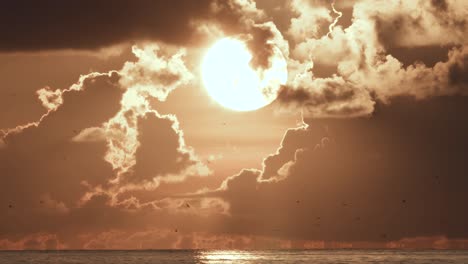 Sonne-In-Wolken-Mit-Vogelsilhouetten,-Die-In-Entfernung-Durch-Ozeanwasser-Fliegen