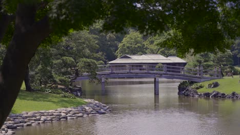 Casa-De-Té-En-Los-Famosos-Jardines-Hamarikyu-En-Tokio-En-La-Distancia-Con-Un-Puente-De-Madera-En-Frente