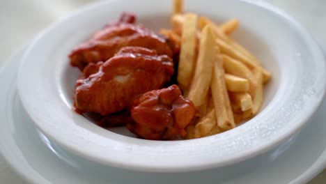 Buffalo-chicken-wings-with-french-fries-served-on-a-white-plate