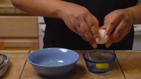 Woman-cracks-open-an-egg-in-a-bowl-on-the-kitchen-counter