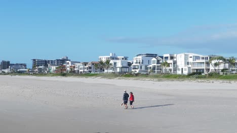 Lovely-Couple-Walking-On-The-Beach-Shore---Seaside-Hotels-At-Palm-Beach---Gold-Coast,-QLD,-Australia