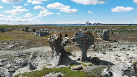 Pair-of-odd-rock-formations-on-flat-land-with-cityscape-in-background