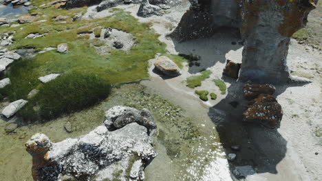 Aerial-view-of-rock-formations-on-land-and-in-water-at-sea-coast